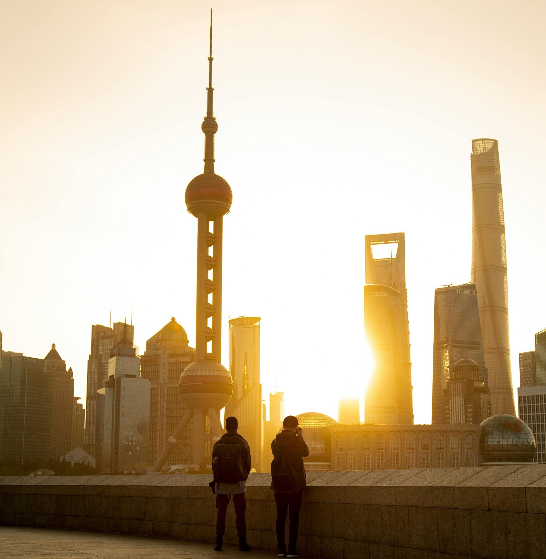Silhouettes of people against the stunning Shanghai skyline at sunset, featuring iconic skyscrapers.
